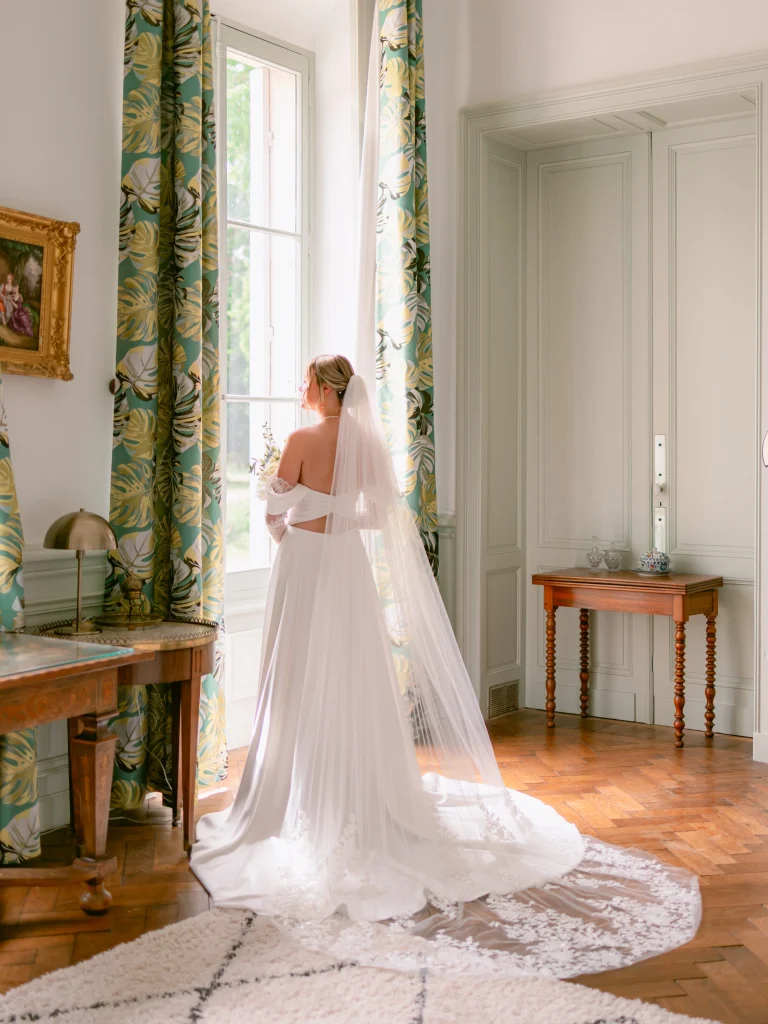 A bride looking out the window of the magnificent Château de Sannes
